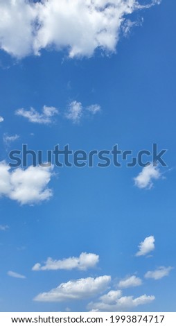 Vertical picture of white clouds in the clear blue sky on a sunny day.