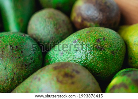 Green ripe avocados. Concept of healthy fruit also useful in cosmetics. Fresh healthy avocado on a table. Stack of avocado in grocery store. Industry of selling products. Spinning. Close up