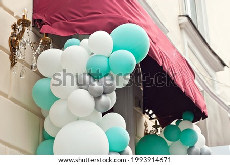 The entrance to the store is decorated with colorful balls. White and green balloons close up.