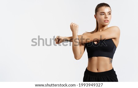 Determined, strong and healthy sports woman, stretching, stretch her arms, warm up for workout in gym, looking away. Silhouette of young athlete prepare body for exercises, white background