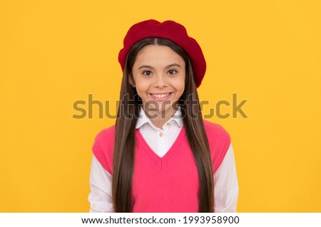 happy teen school girl in french beret on yellow background, childhood