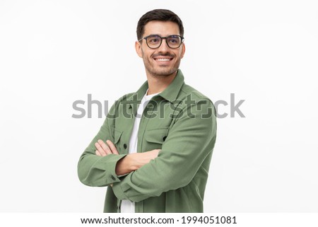 Confident young man in casual green shirt looking away, standing with crossed arms isolated on gray  Royalty-Free Stock Photo #1994051081