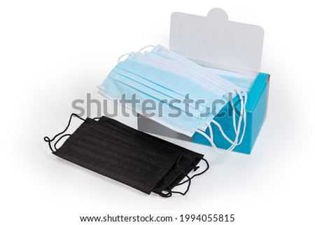 Several black protective face masks and open cardboard packaging of the light blue disposable medical masks on a white background
