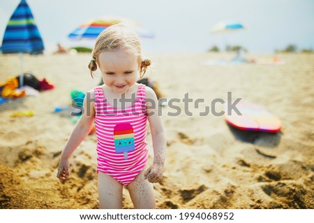 Happy little girl having fun on the beach at Mediterranean sea in France. Cheerful kid enjoying vacation at the sea. Outdoor summer activities for children