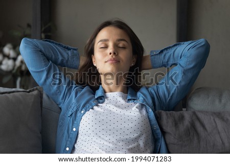 Head shot happy relaxed attractive young woman sleeping on cozy sofa, breathing fresh air, napping daydreaming or meditating alone on weekend, enjoying mindful peaceful moment in living room. Royalty-Free Stock Photo #1994071283