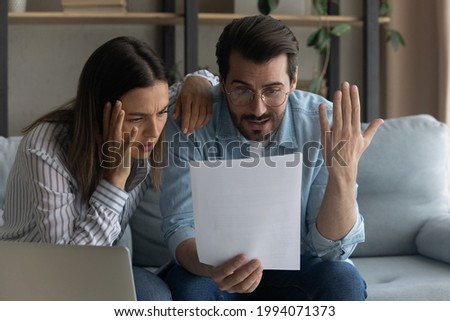 Anxious stressed unhappy young man woman couple looking through paper correspondence, feeling dissatisfied nervous reading bad news, received bank loan rejection notification or eviction letter. Royalty-Free Stock Photo #1994071373