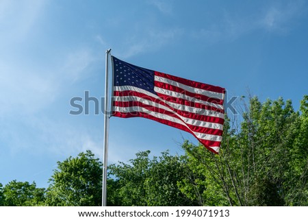 American Flag On Pole With Blue Skies And Forest Trees.