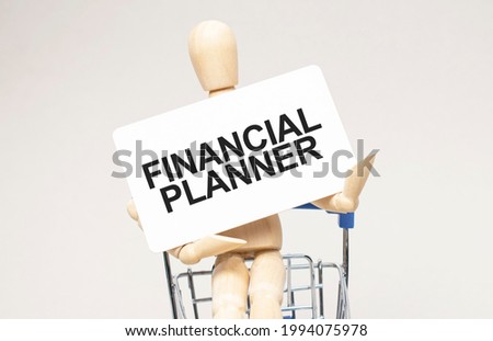 Wooden model of a human in a shopping cart. Grey background. Text FINANCIAL PLANNER