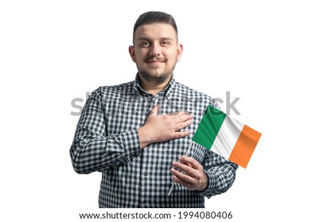 White guy holding a flag of Ireland and holds his hand on his heart isolated on a white background With love to Ireland.