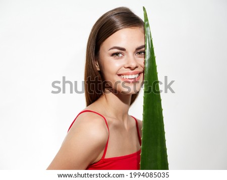 portrait of happy woman with green aloe leaf on light background cropped view