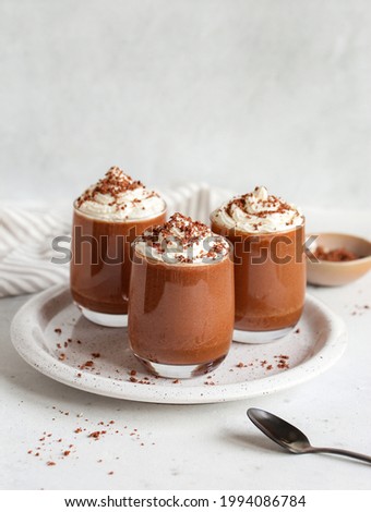 Healthy vegan chocolate mousse with vegan cream topping  in glasses on white background. Homemade Chocolate mousse from aquafaba.  Royalty-Free Stock Photo #1994086784