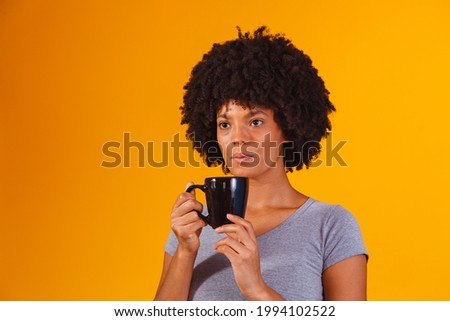 afro woman taking tea on yellow background