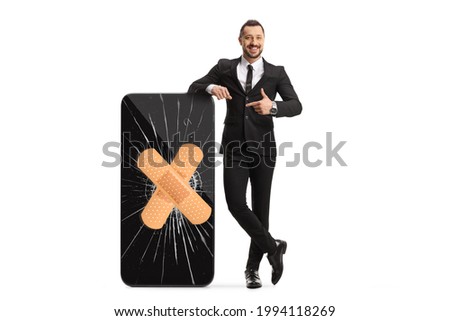 Smartphone with a broken screen and bandage and a businessman pointing isolated on white background