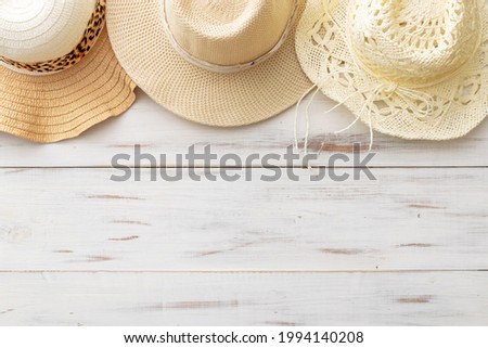 summer background: three straw hats on a light wooden background