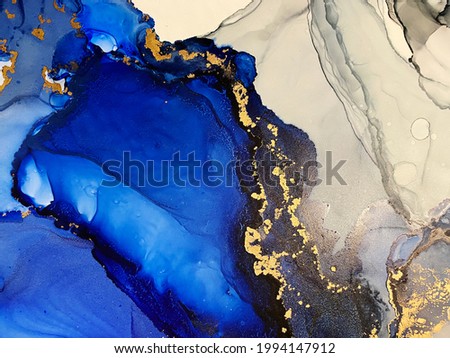 Abstract blue background with gold — beautiful smudges and stains made with alcohol ink and golden metallic. Fragment of art with ultramarine texture resembles watercolor or aquarelle painting.