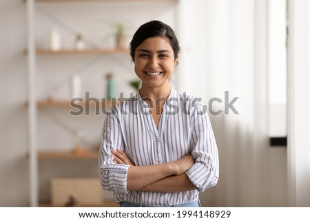 Portrait of happy young Indian female renter tenant stand arms crossed pose in living room at home. Smiling millennial successful confident mixed race ethnicity woman show leadership at workplace. Royalty-Free Stock Photo #1994148929