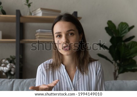 Beautiful confident young woman looking at camera, holding distant online web call conversation or passing distant job interview. Happy female blogger recording video, streaming live in social network Royalty-Free Stock Photo #1994149010