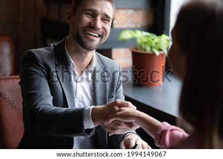 Candid handsome young man shaking hands with woman, getting acquainted on speed dating in cozy cafe. Happy millennial guy enjoying pleasant meeting with female friend, communication concept. Royalty-Free Stock Photo #1994149067