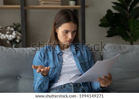 Anxious frustrated unhappy young woman looking through paper letter, feeling stressed of reading unpleasant information or bad news, financial bank notification with mistake or loan rejection notice. Royalty-Free Stock Photo #1994149271