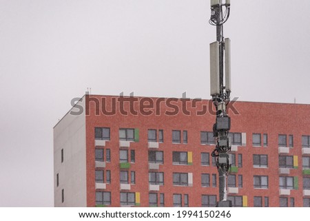 Mobile operator equipment. 3G and 4G transmitters hang high on a pole. Cell tower in the city.
