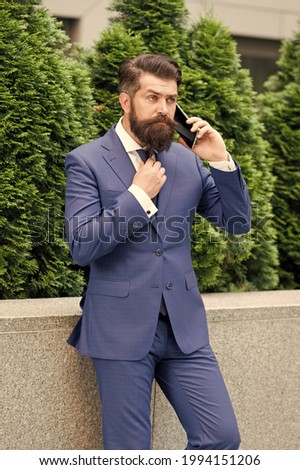 Stay connected. Businessman talk mobile phone. Handsome bearded man with cell phone outdoor. Mobile lifestyle. Business communication. Mobile technology. Business call. Stylish guy wear tuxedo