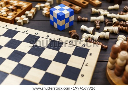 Chess board and chess pieces, wooden cubes, puzzle games on dark wooden table. Popular logic games for logical thinking.