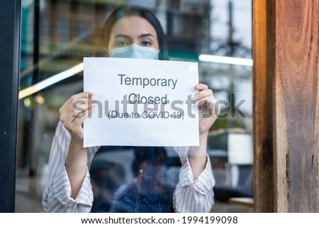 Caucasian Coffee shop owner or waitress wear mask to prevent from Coronavirus, turns Temporary closed sign to shut down small business due to financial crisis from COVID-19 lockdown and quarantine.