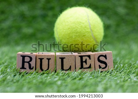 Tennis rules with ball and word on green grass