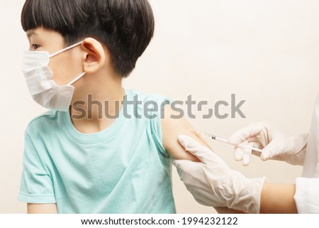COVID 19 Vaccines for Kids concept. An adorable asian boy with medical face mask just got his first dose vaccine by a nurse in hospital. Authorized, Approved, Trial, Safe, Available, Back to school.