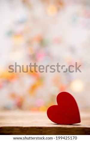 Red wooden heart on a wooden background with boke background.