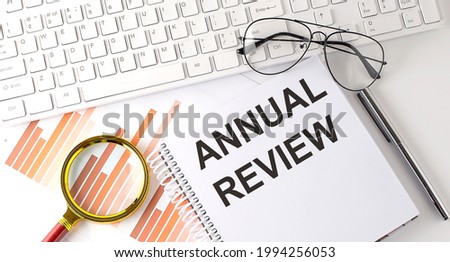 ANNUAL REVIEW text written on notebook with keyboard, chart,and glasses