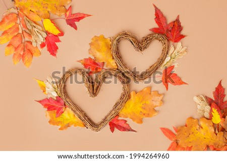 Hello autumn. Autumn Background with heart frame and leaves on beige brown neutral board. Fall season backdrop, greeting card, copy space