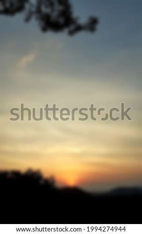 Blurry landscape sunset scenery on-mountain In the evening, with a silhouette of trees in A forest and orange sky, gray clouds, vertical picture concept.