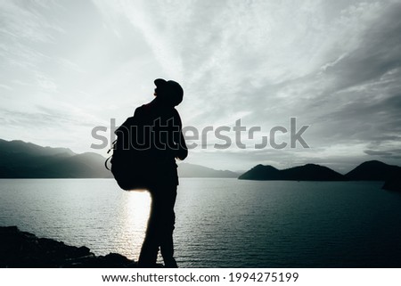 young teen Caucasian boy hipster man silhouette adult backpacker enjoying camera on beautiful landscape scenery view jungle mountains forest at Kanchanaburi water river lake dam , Thailand