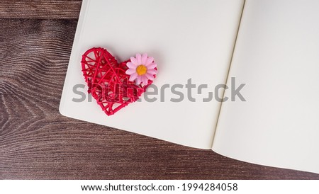 Blank notebook and pen with red heart shape decoration on wooden table background. Wedding, Romantic and Happy