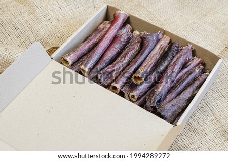 Full Cardboard Pet Treat Box on burlap fabric. Dried dog goodies. Delicious Red Beef Gullet Sticks. Bovine esophagus. Selective focus