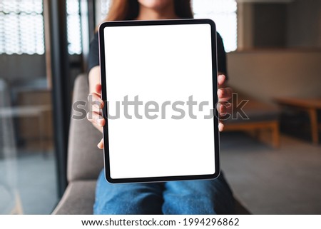 Mockup image of a woman holding and showing digital tablet with blank white desktop screen