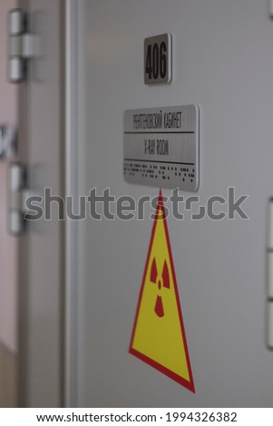entrance into the roengen examining room with plate with signs on russian, english and braille and sign of radiation hazard