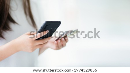 Focus on hand. young asian woman using smart phone shopping or paying online and blur another hand holding credit card