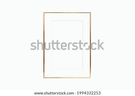 Thin gold frame with mat on a white wall. Mockup for your design.