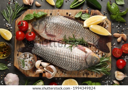 Fresh raw crucian carps and ingredients on grey table, flat lay. River fish Royalty-Free Stock Photo #1994349824
