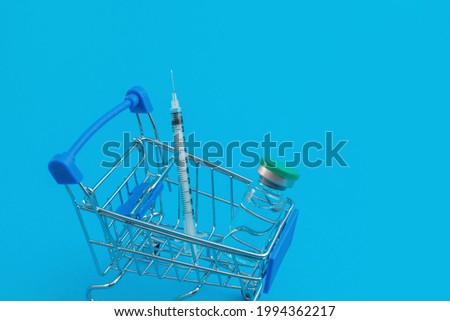 supermarket trolley with syringes and ampoule on blue background