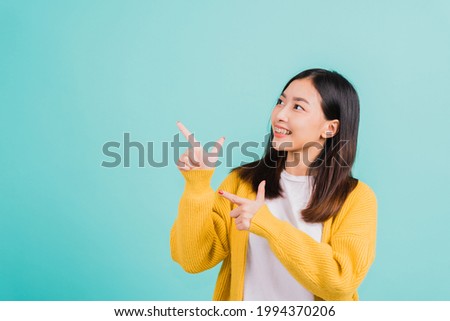 Portrait Asian beautiful young happy woman teen smiling show white teeth she's pointing finger up to side empty space studio shot isolated on blue background, Dental health concept