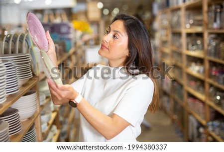 Woman selecting crockery in tableware store closeup. High quality photo