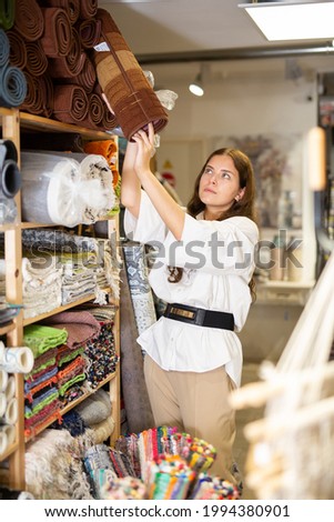 Female shopper chooses floor mat in textile store