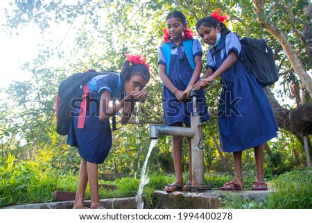 Indian Rural School Girls drinking water from Tubewell at village Royalty-Free Stock Photo #1994400278