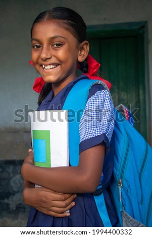 Side view Smiling Indian Rural School Girl holding notebook in school Royalty-Free Stock Photo #1994400332
