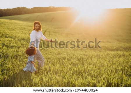 Mother with black baby girl having fun together in field