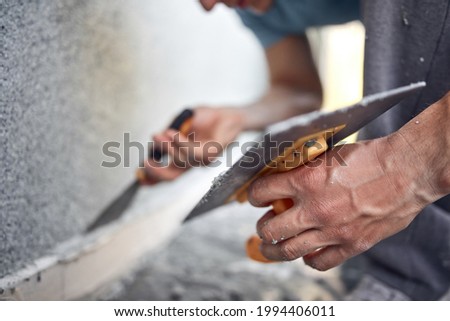 Man working on a house facade. Royalty-Free Stock Photo #1994406011