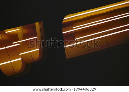 Luminescent lamps glow in darkness. Abstract architecture and modern interior background. Lighting elements of suspended ceiling. Minimal design. Decorative electric energy flow. Geometric structure Royalty-Free Stock Photo #1994406329